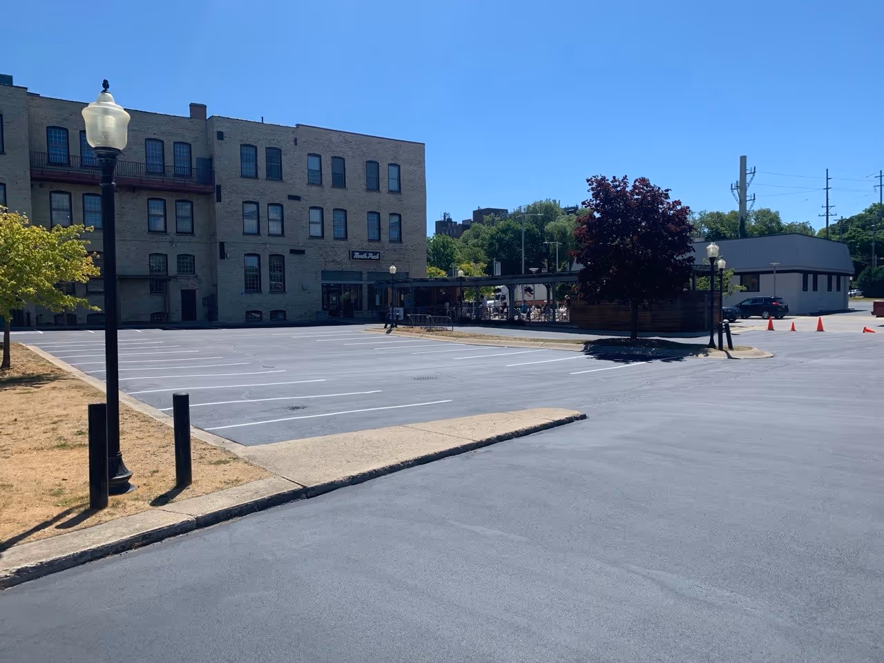 Overview of the completed asphalt repair, sealcoating, and striping project for the multi-business complex managed by Schmidt-Rogers Management. The lot is fully restored and ready for the public, serving North Peak, Kilkenny's, and Stafford-Smith.