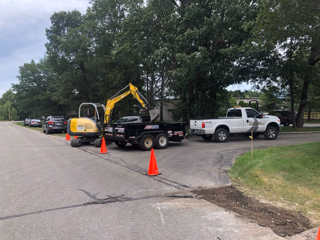 A Wacker Neuson 3507 excavator removing damaged asphalt at the entrance of VP Demand Creations. The project involves structural excavation and removal of failed pavement to ensure a long-lasting repair at this high-traffic commercial entrance.