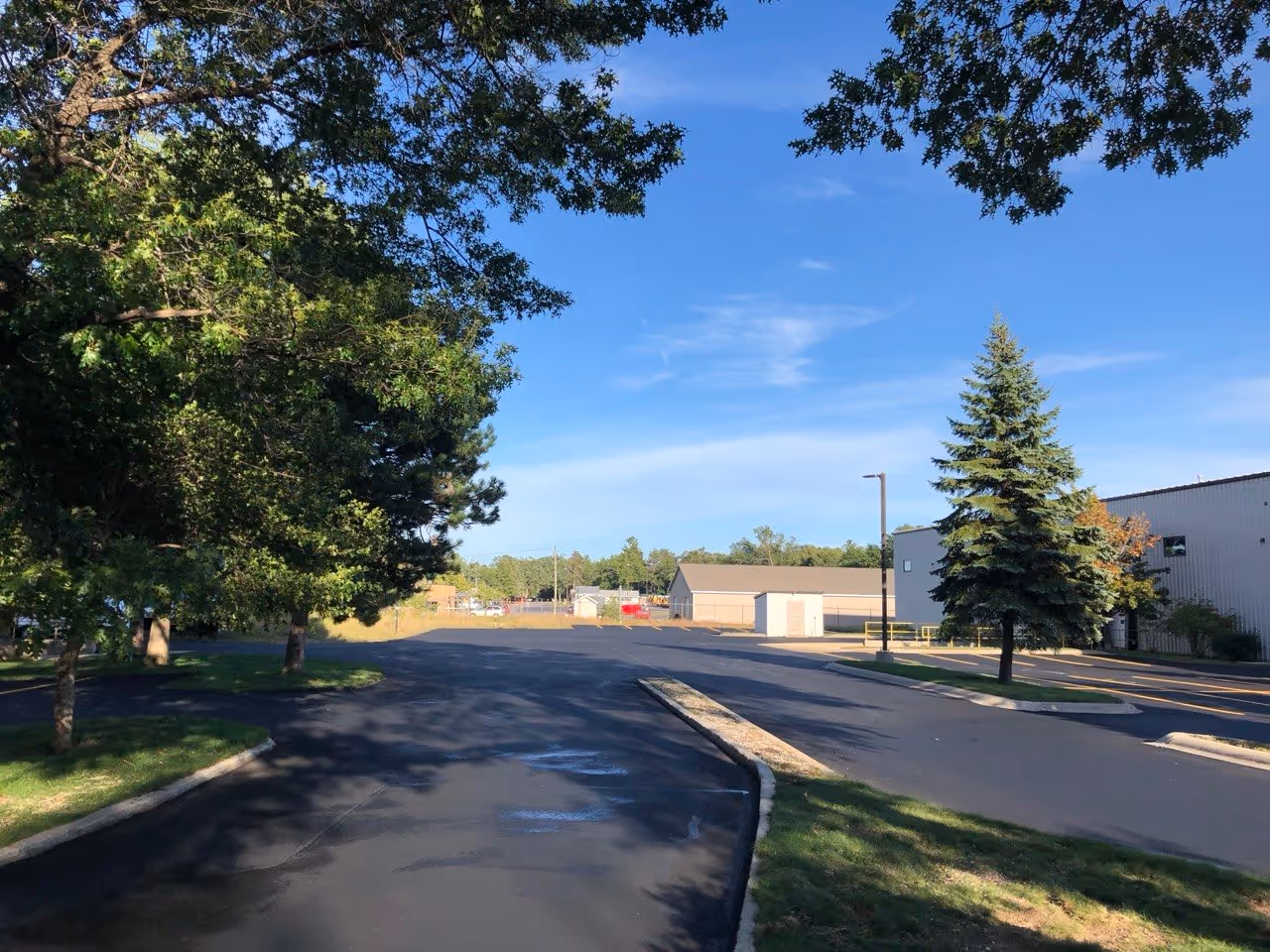 An overview of the completed sealcoating project at VP Demand Creations on Aero-Park Dr. Both entrances and the main parking lot feature a uniform, deep-black protective finish that restores the property's aesthetics and pavement life.