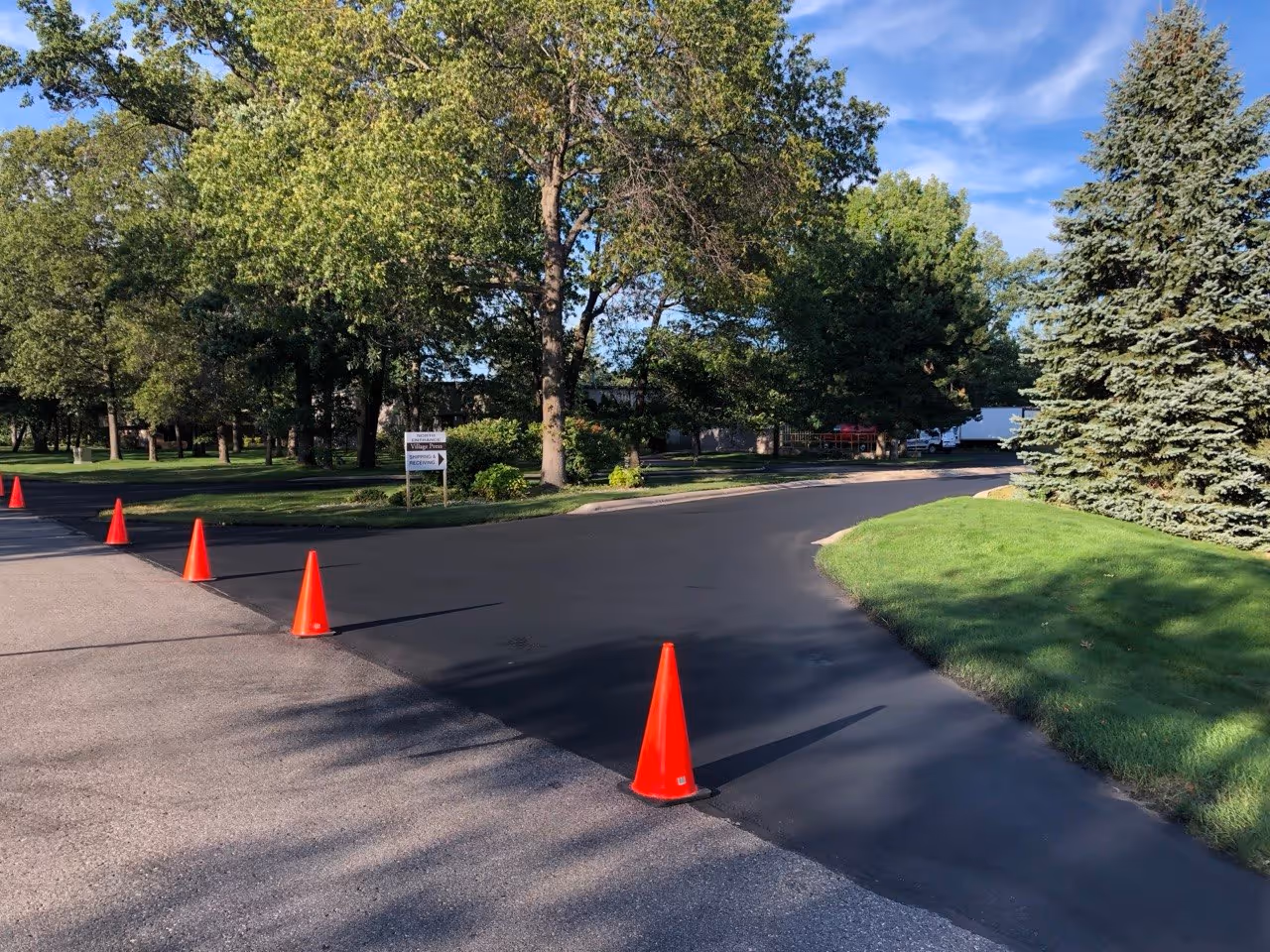 A freshly sealed entrance at VP Demand Creations blocked with orange safety cones during the drying phase. Proper site barricading ensures the commercial grade sealant cures undisturbed by vehicle traffic on Aero-Park Dr.
