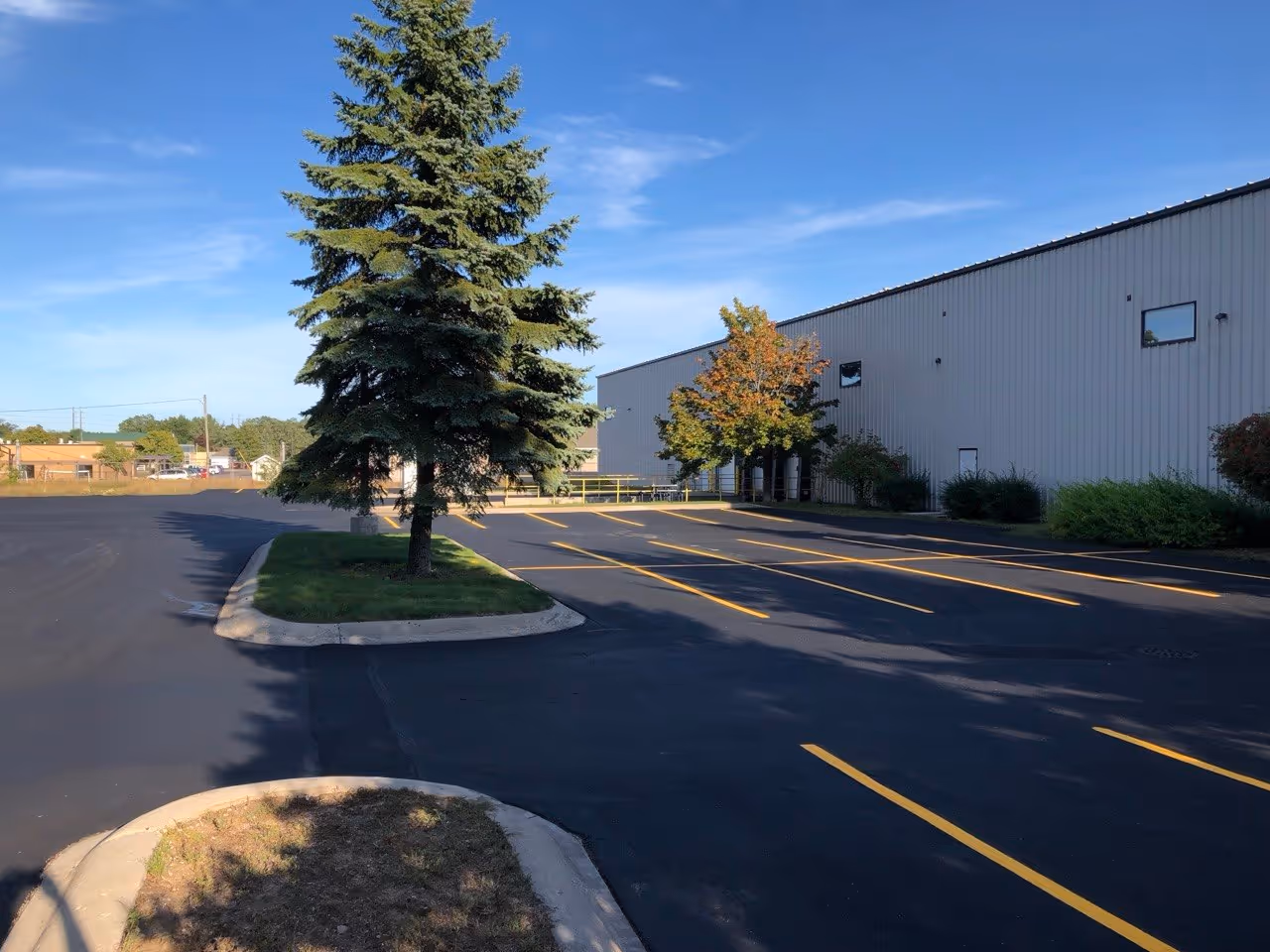 The finished truck turn-around, loading dock, and employee parking lot at VP Demand Creations. The area features a fresh sealcoat and precision yellow parking lines, optimized for heavy logistical traffic and organized staff parking.