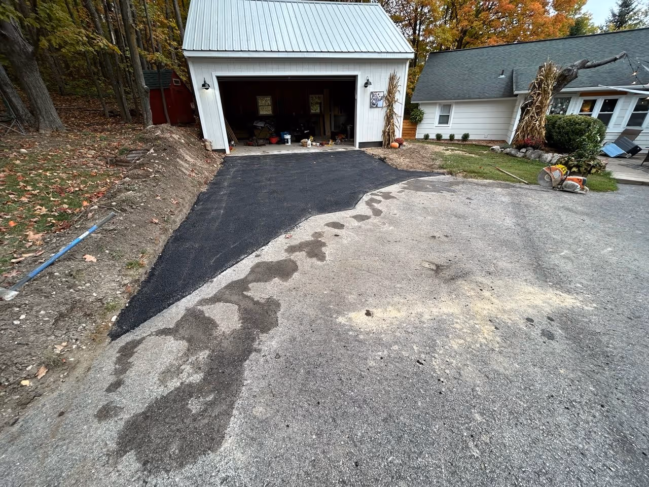 Completed asphalt driveway extension for a new garage construction at the intersection of Barnes Rd and Silver Lake Rd in Traverse City, Michigan.