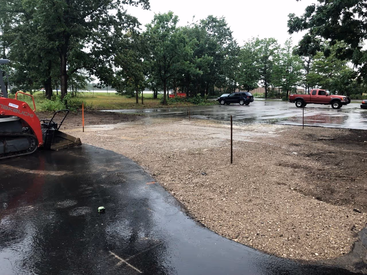 A Takeuchi skid steer overlooking the newly compacted 22A gravel base for the inter-lot driveway at Hagerty Insurance Agency. This critical step ensures the sub-base has reached maximum density before the paving phase on Aero-Park Dr.