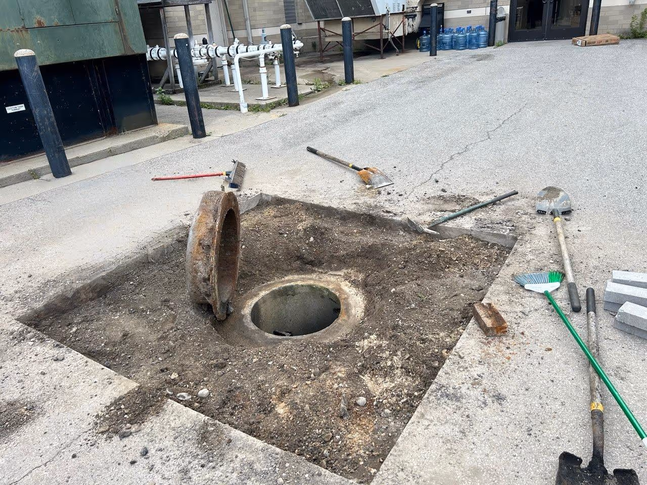An image showing the area of a failed driveway drain with asphalt and concrete removed, and the top of the catch basin ready for structural rebuilding in Northern Michigan.