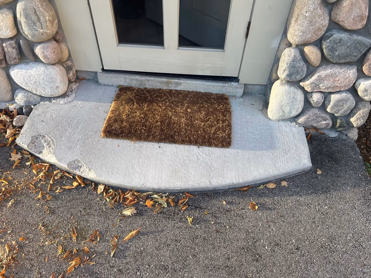 A damaged concrete porch step with missing chunks caused by snow plow impact at a private residence on Big Glen Lake in Glen Arbor, MI, requiring professional concrete patching and repair.