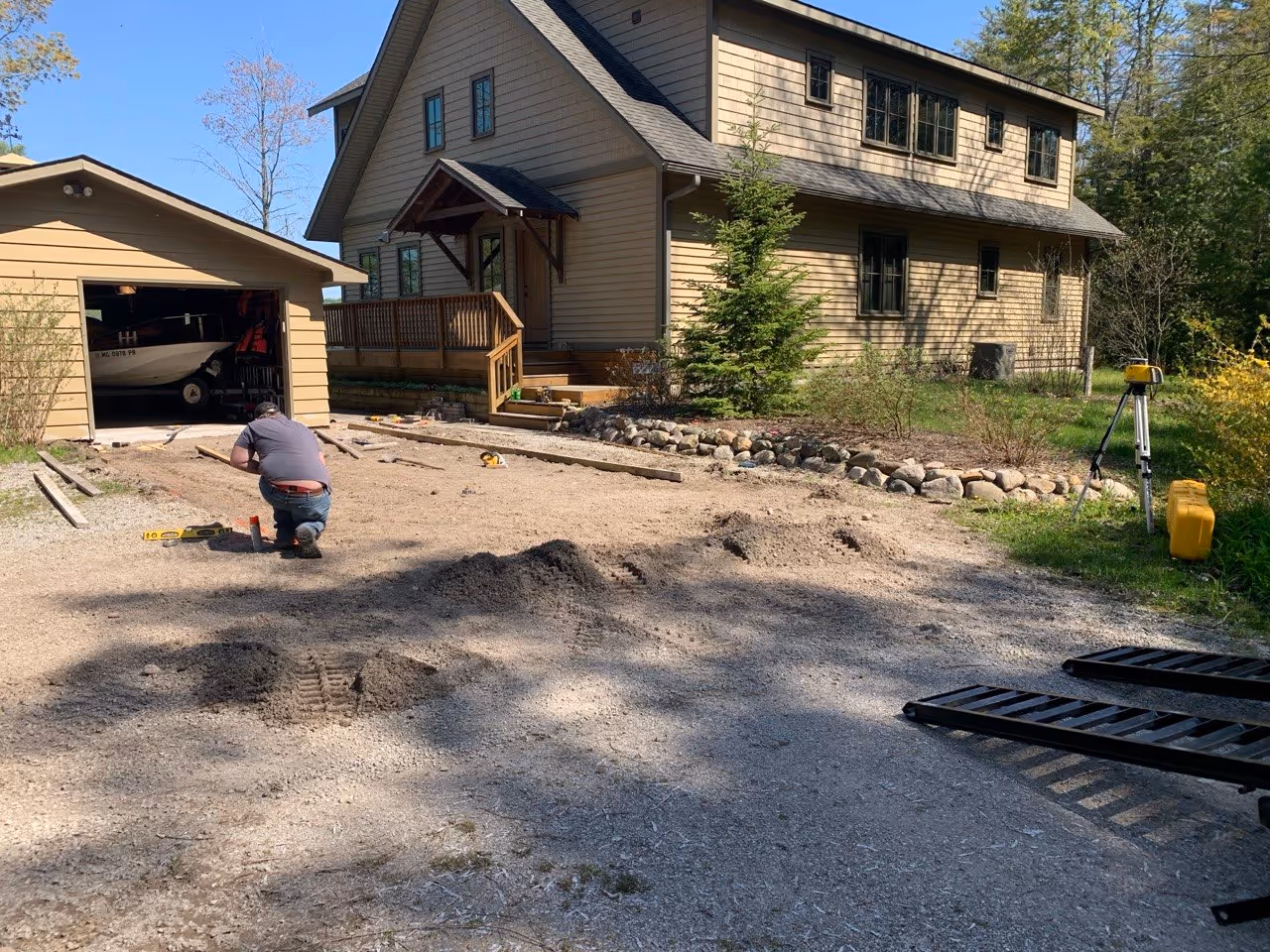 An area of a driveway being excavated at a Lime Lake home in Lake Leelanau County. A worker installs wooden form boards in preparation for a new concrete pad off S Maple City Rd.