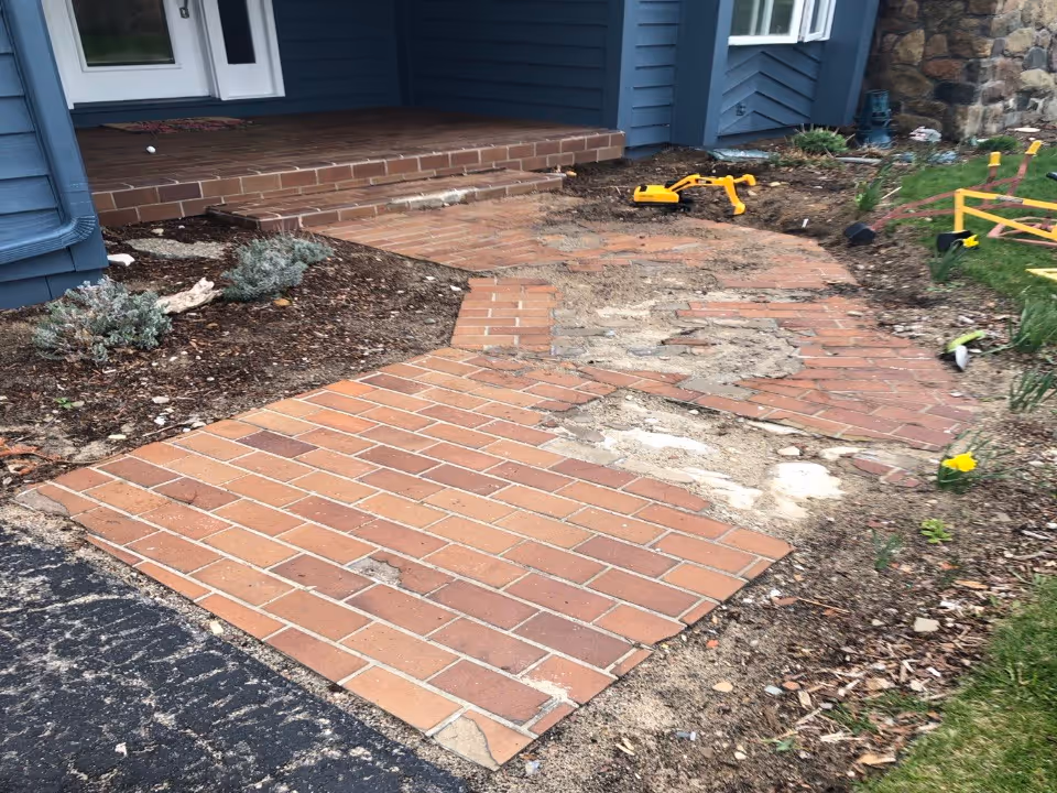 A failing concrete sidewalk, front porch, and garage apron with missing chunks and surface scaling at a residence on Old Mission Peninsula in Traverse City, MI.