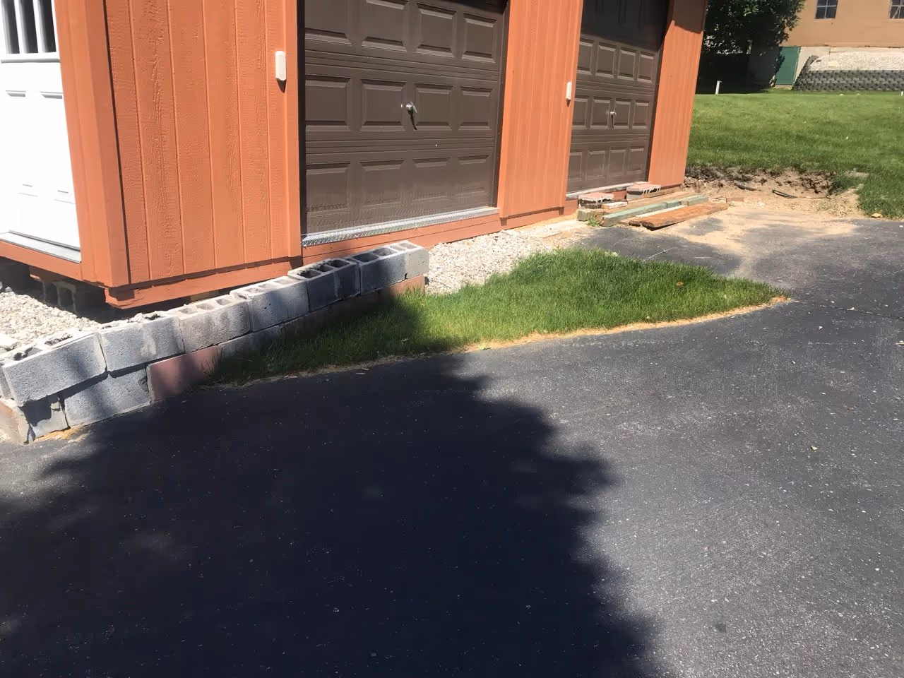 A new portable garage on Lake Leelanau showing the transition area where grass and an existing asphalt driveway meet before excavation for a concrete apron.
