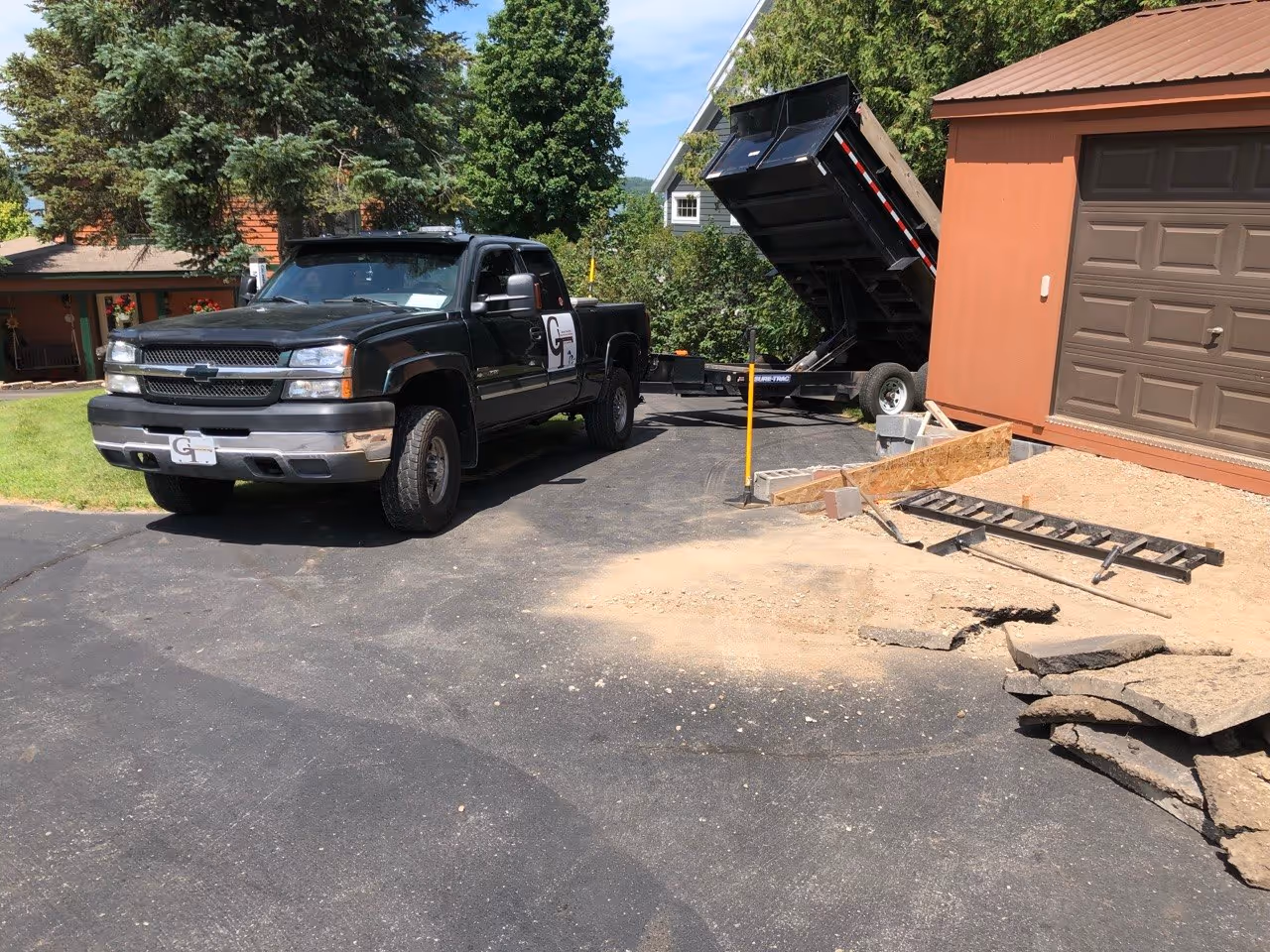 A Chevy 2500 Duramax diesel with a dump trailer unloading stone for retaining wall backfill and concrete sub-base at a residence off S Lakeview Rd.
