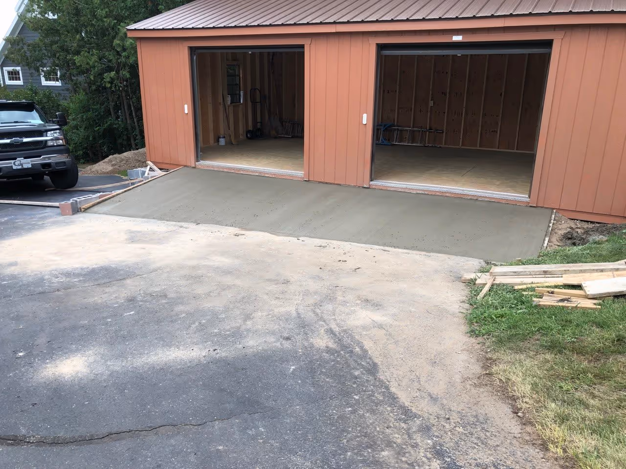 Freshly poured and broom-finished concrete garage apron providing a durable, non-slip transition for the new portable building.