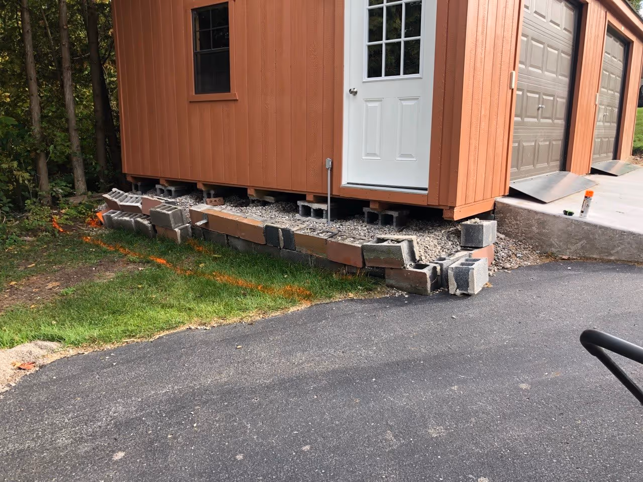 The cured concrete garage ramp with markings for the upcoming retaining wall construction to support the raised elevation of the site.
