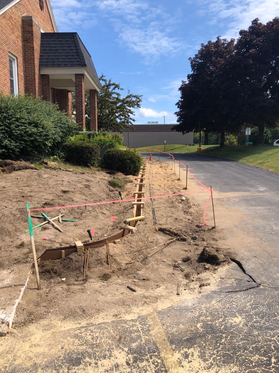 A detailed view of curved concrete curb formwork designed to redirect water flow and protect the parking lot sub-base at Faith Reformed Church.