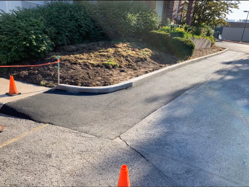 The final compacted asphalt patch integrated with a new concrete curb to solve drainage issues at the corner of E Front St and Peninsula Dr.