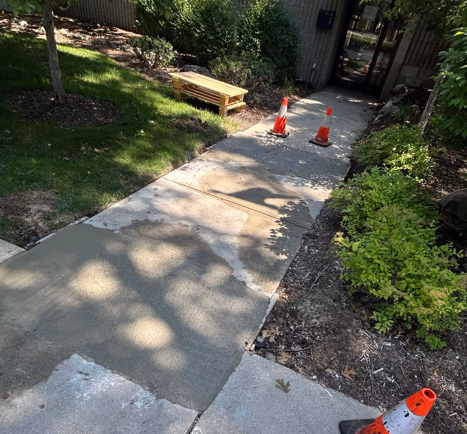 Freshly installed concrete sidewalk sections at a commercial complex in Traverse City, replacing broken and scaled pavement.