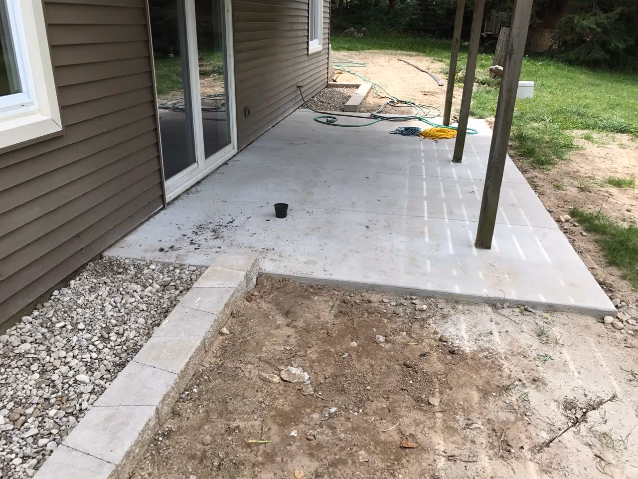 The completed concrete patio with forms removed and site cleaned up, providing a solid surface in front of the home's sliding door.