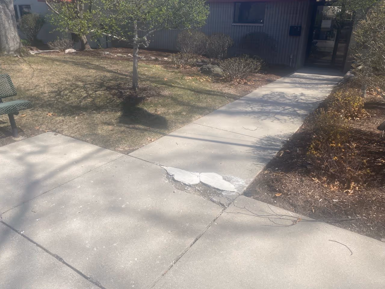 A high-traffic commercial sidewalk at VP Demand Creations in Traverse City showing advanced concrete scaling and surface deterioration, creating a significant safety risk for employees and visitors.