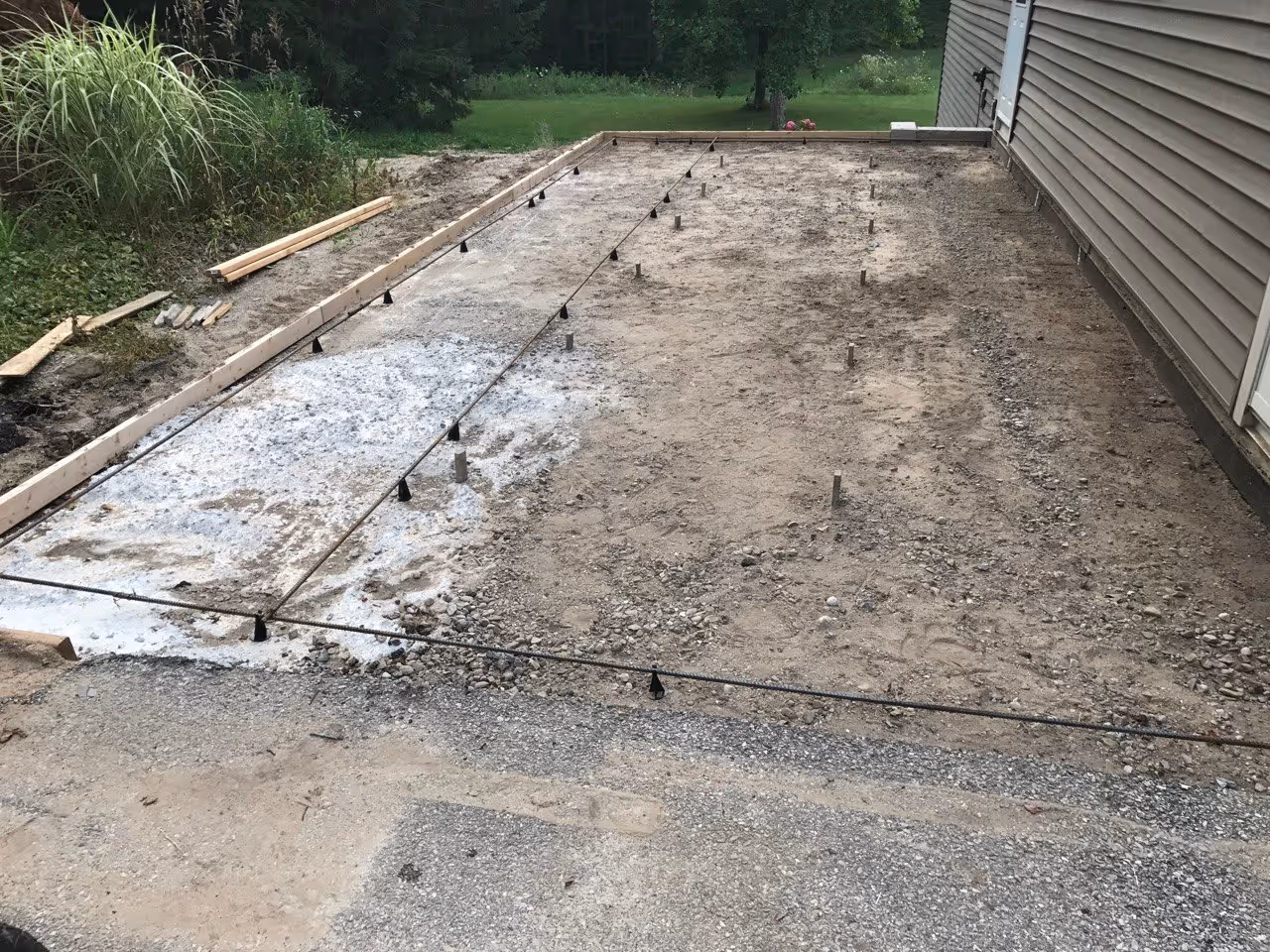 Excavated and formed area on S Coleman Rd for a residential driveway extension. Steel rebar reinforcement is installed around the edges for added structural strength before the concrete pour.