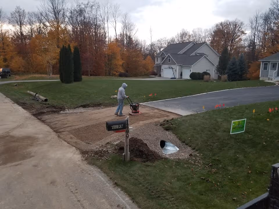 High-density compaction of the gravel base over a new culvert in Traverse City to eliminate air pockets and ensure the new asphalt patch won't sink over time.