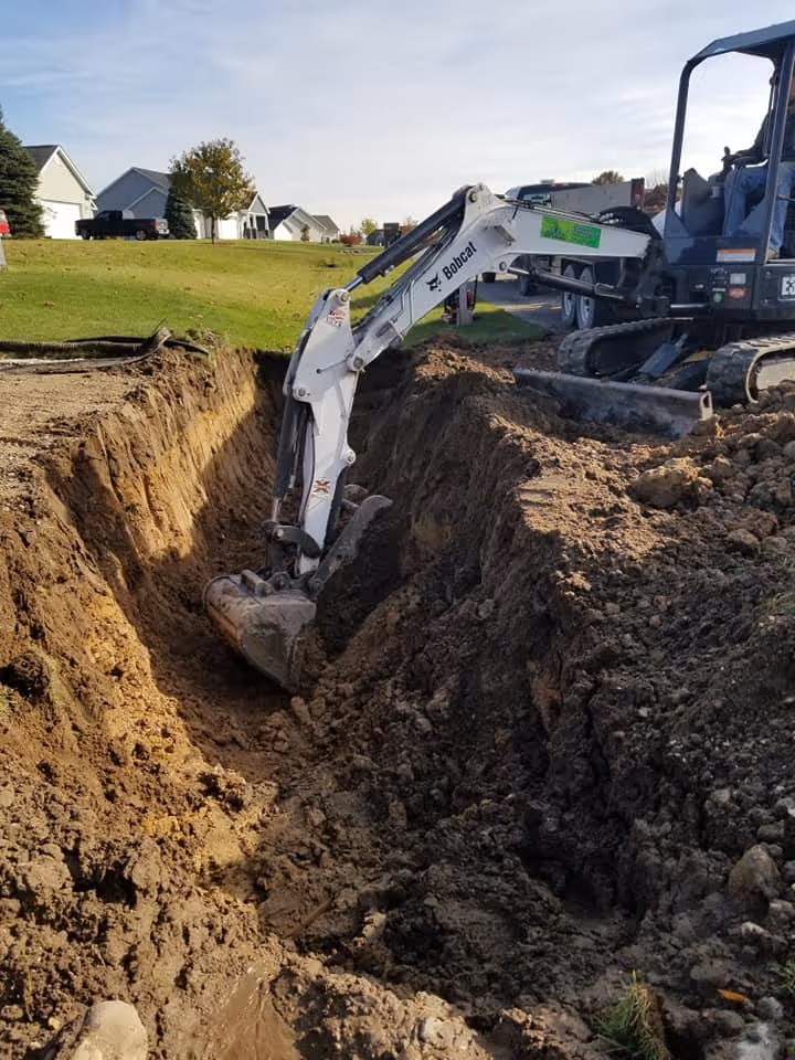 Close-up of a precision-dug trench in Traverse City, being graded to receive a structural stone bedding which prevents future pipe settling and movement.