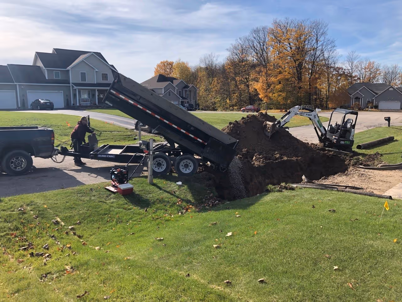 A dump trailer delivering clean, crushed stone to create a stable, free-draining foundation for the new HDPE culvert installation in Traverse City.