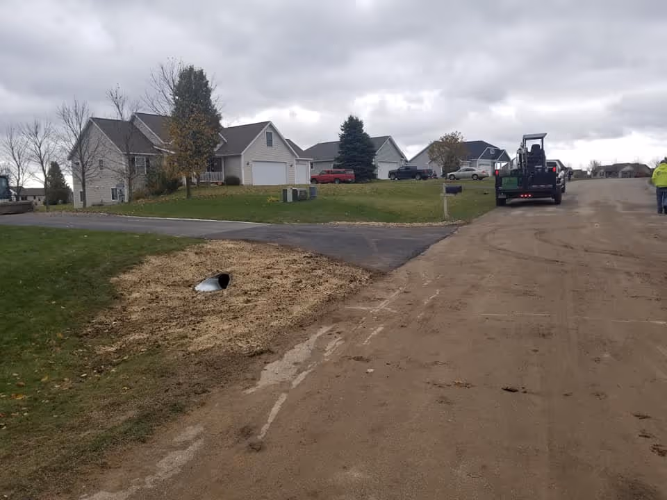 The completed driveway culvert replacement in Traverse City, featuring a level asphalt surface and fully restored roadside drainage functionality.