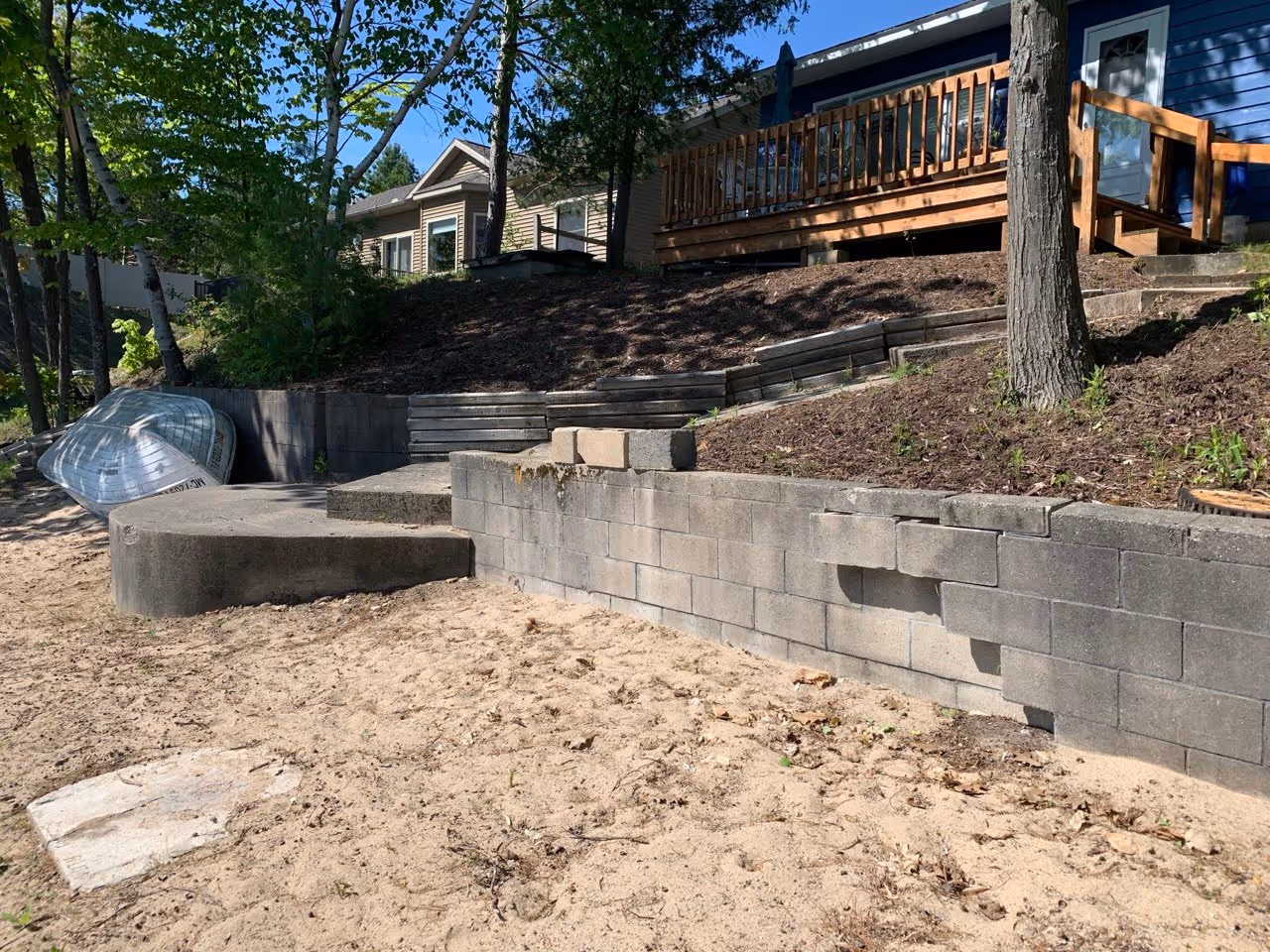 The initial state of the property: Crumbling concrete steps and a failed retaining wall on Van Petten Dr, highlighting the urgent need for professional shoreline restoration.