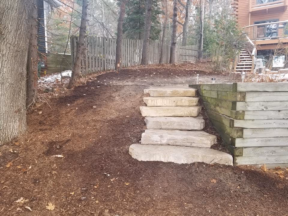 Six natural stone outcropping steps set into the hillside. These steps wrap around an existing retaining wall to provide a durable and aesthetic path to the house.