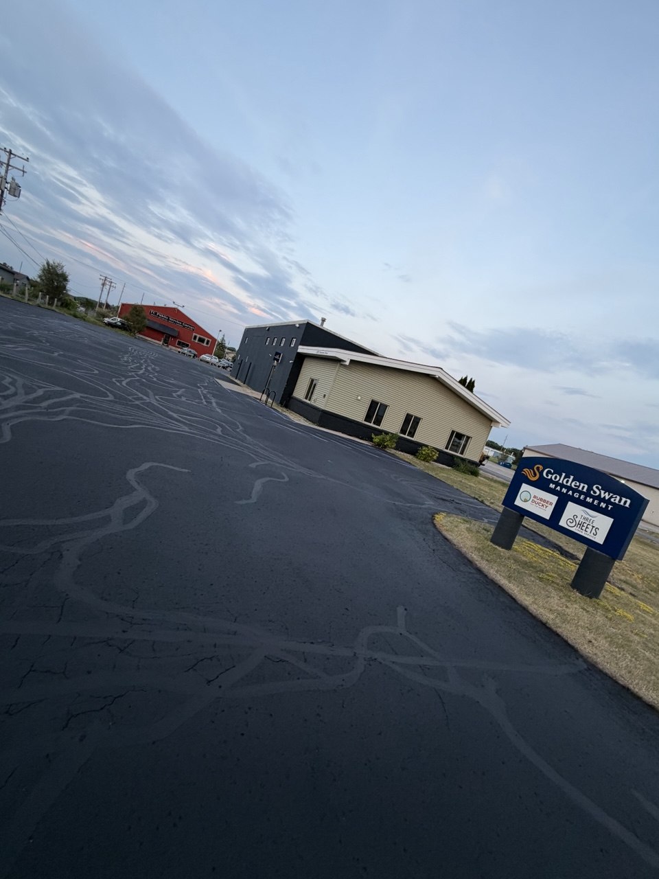 Freshly sealcoated asphalt driveway and parking area for Golden Swan Management located at 2470 Diamond Drive in Traverse City, MI, showing rich black pavement sealant application.