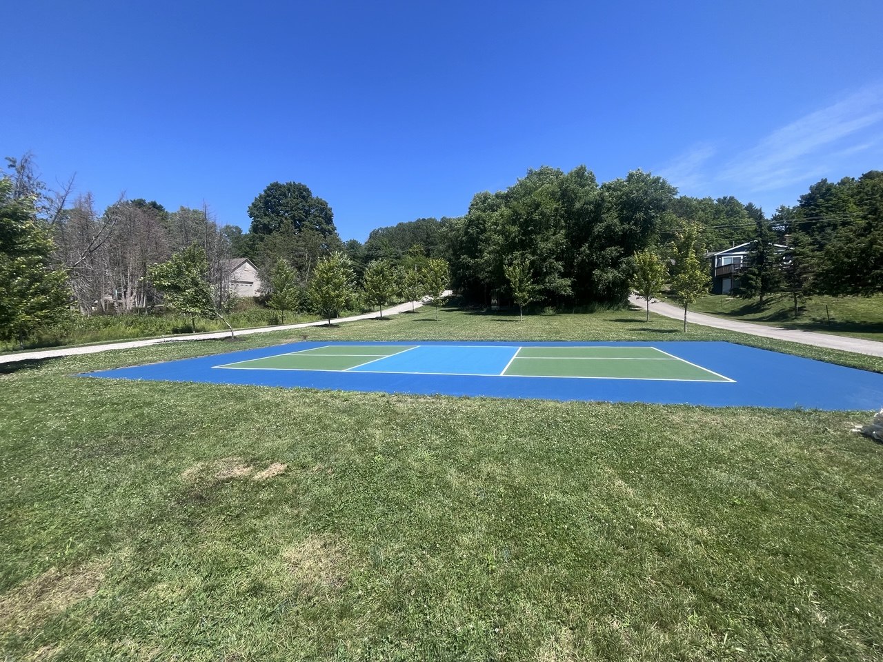 Side perspective view of a fully resurfaced private athletic court on Torch Lake, MI, showcasing high-definition acrylic colors and crisp boundary lines.