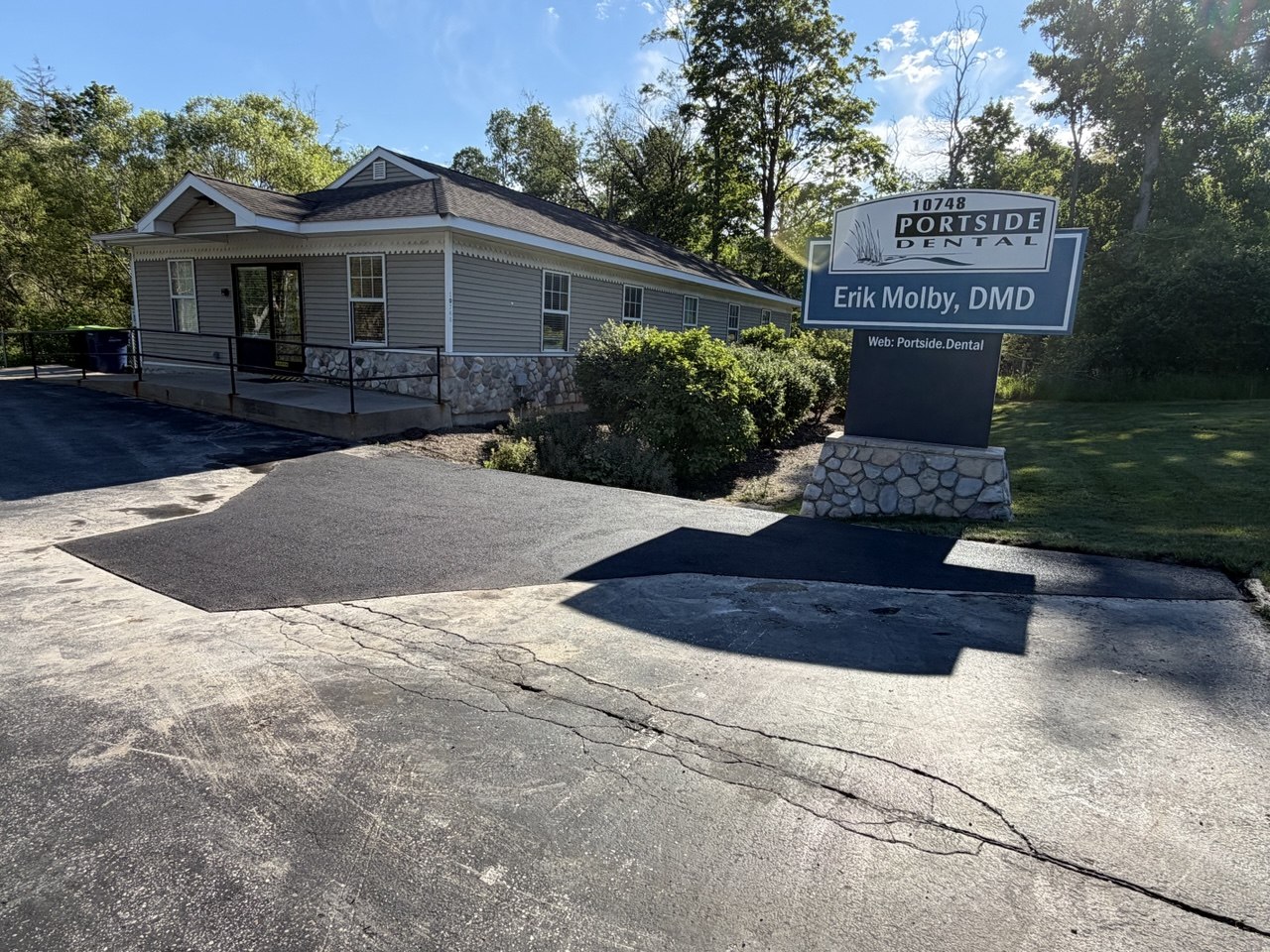 Cut-and-replace commercial asphalt pavement repair in progress at Portside Dental on M-72 in Traverse City, MI, featuring clean saw-cut perimeter edges, excavated base, and compacted hot-mix asphalt patching.