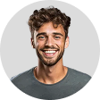 Smiling young man with curly brown hair and beard wearing a gray shirt against a light gray background.