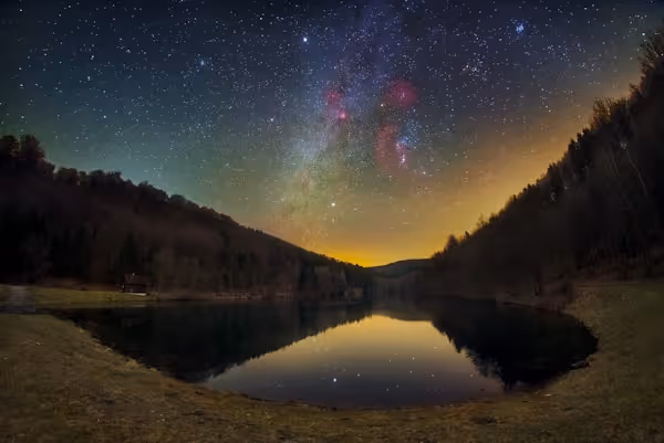 Starry night sky over a calm lake reflecting stars
