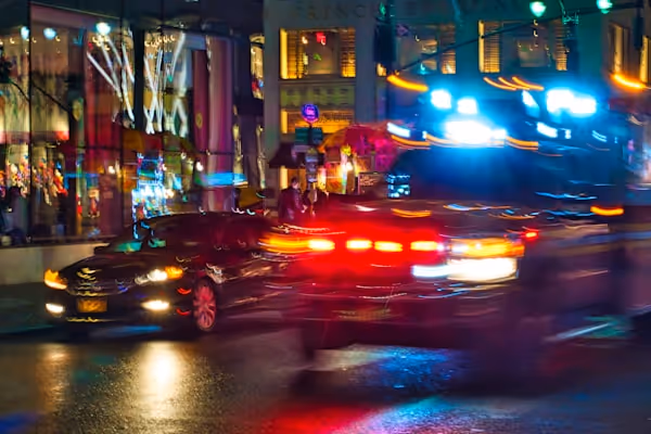 An emergency vehicle moving through nighttime traffic on a New York Street.