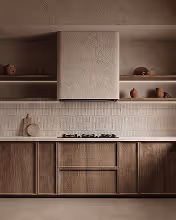 Modern kitchen with wooden cabinets, tiled backsplash, and a textured white range hood.