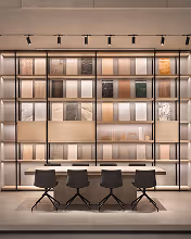 Modern study area with a desk, four chairs, and a decorative shelving wall with books and lights.
