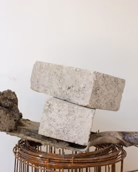Two gray concrete blocks stacked on top of each other on a round wire metal structure.
