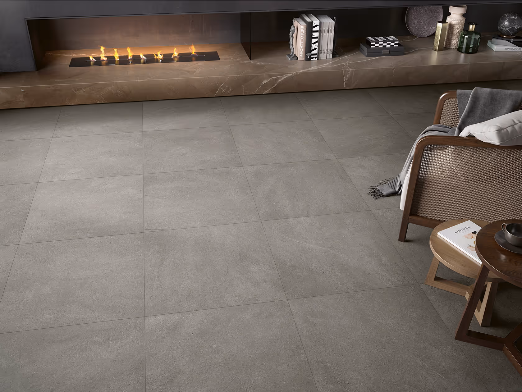 Modern living room corner with gray tiled floor, a lit fireplace, and a chair with a throw and pillow.