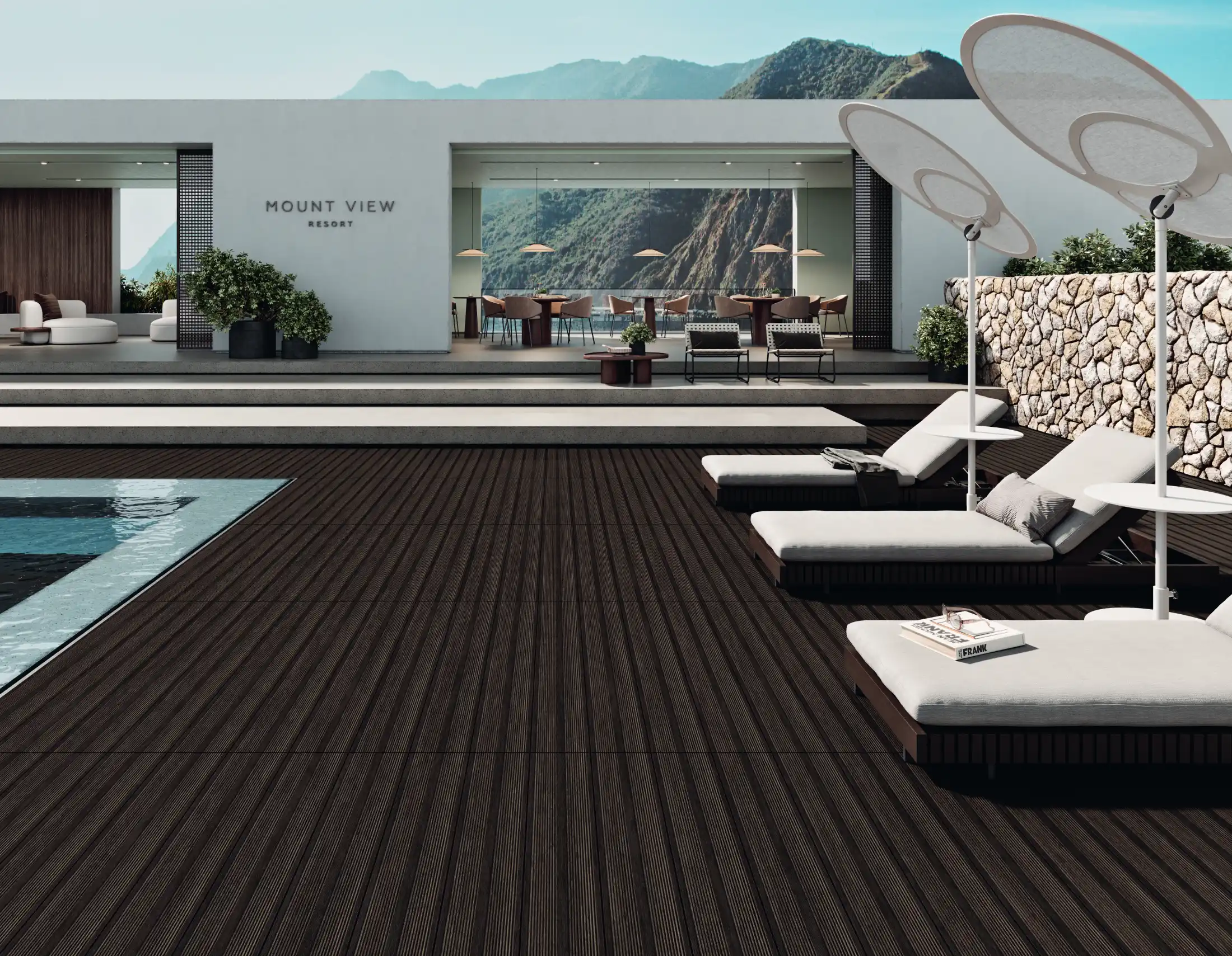 Outdoor resort deck with dark wood flooring, lounge chairs, umbrellas, pool, and mountain view dining area.
