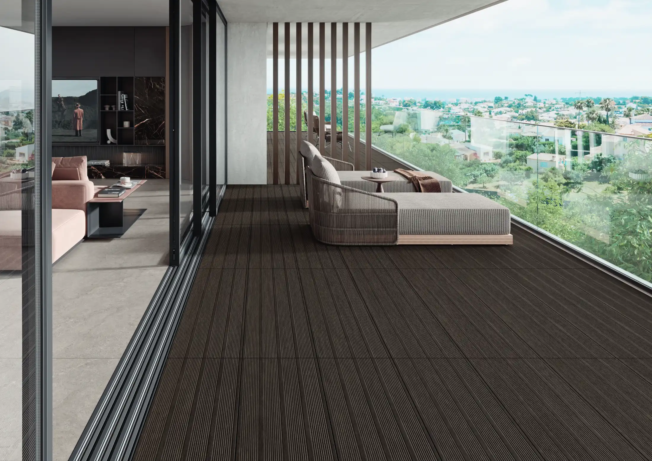 Modern balcony with dark wood decking, two lounge chairs, glass railing, and a city view beyond.