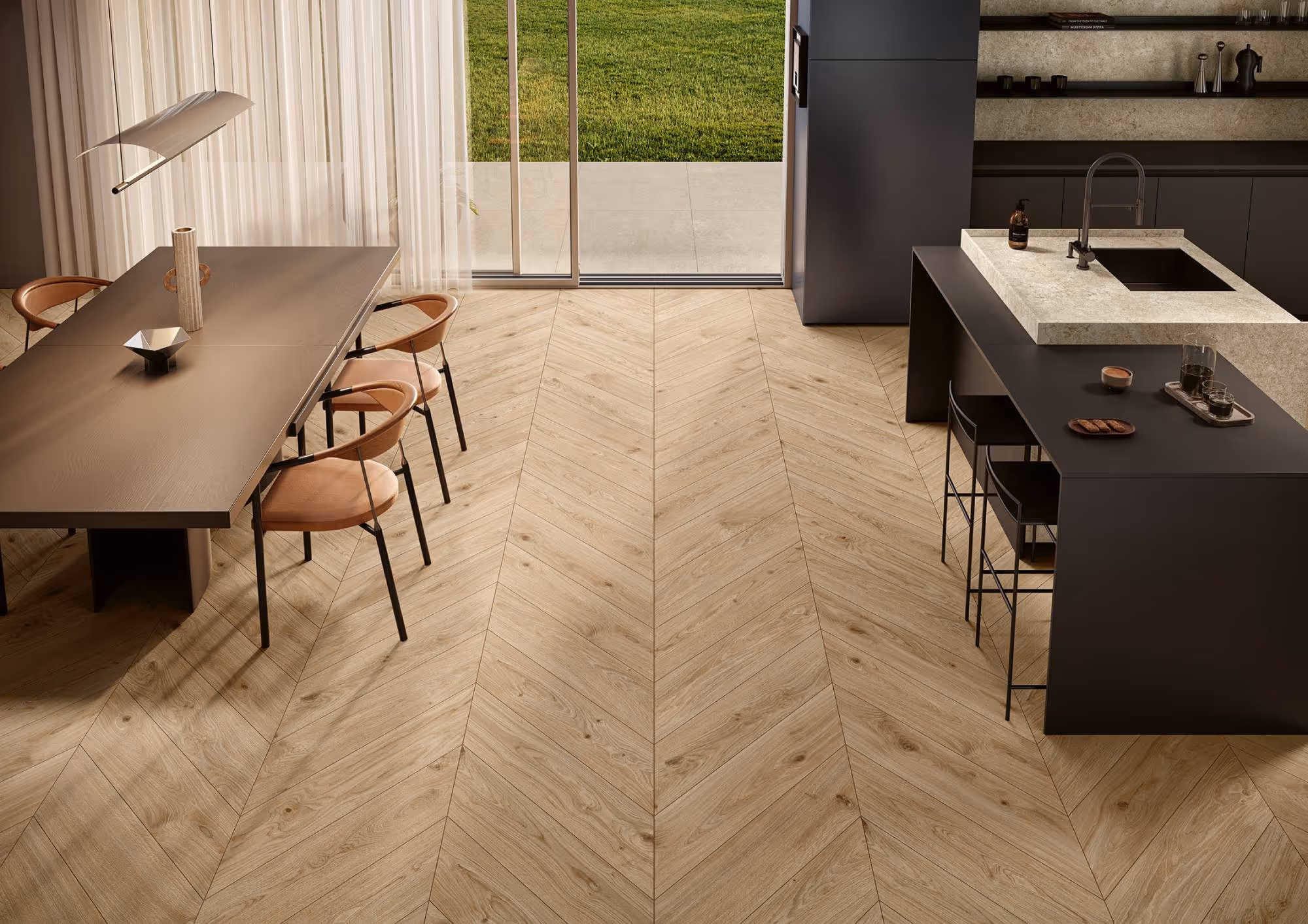 Modern kitchen and dining room with light wood chevron flooring and black furniture by glass doors.