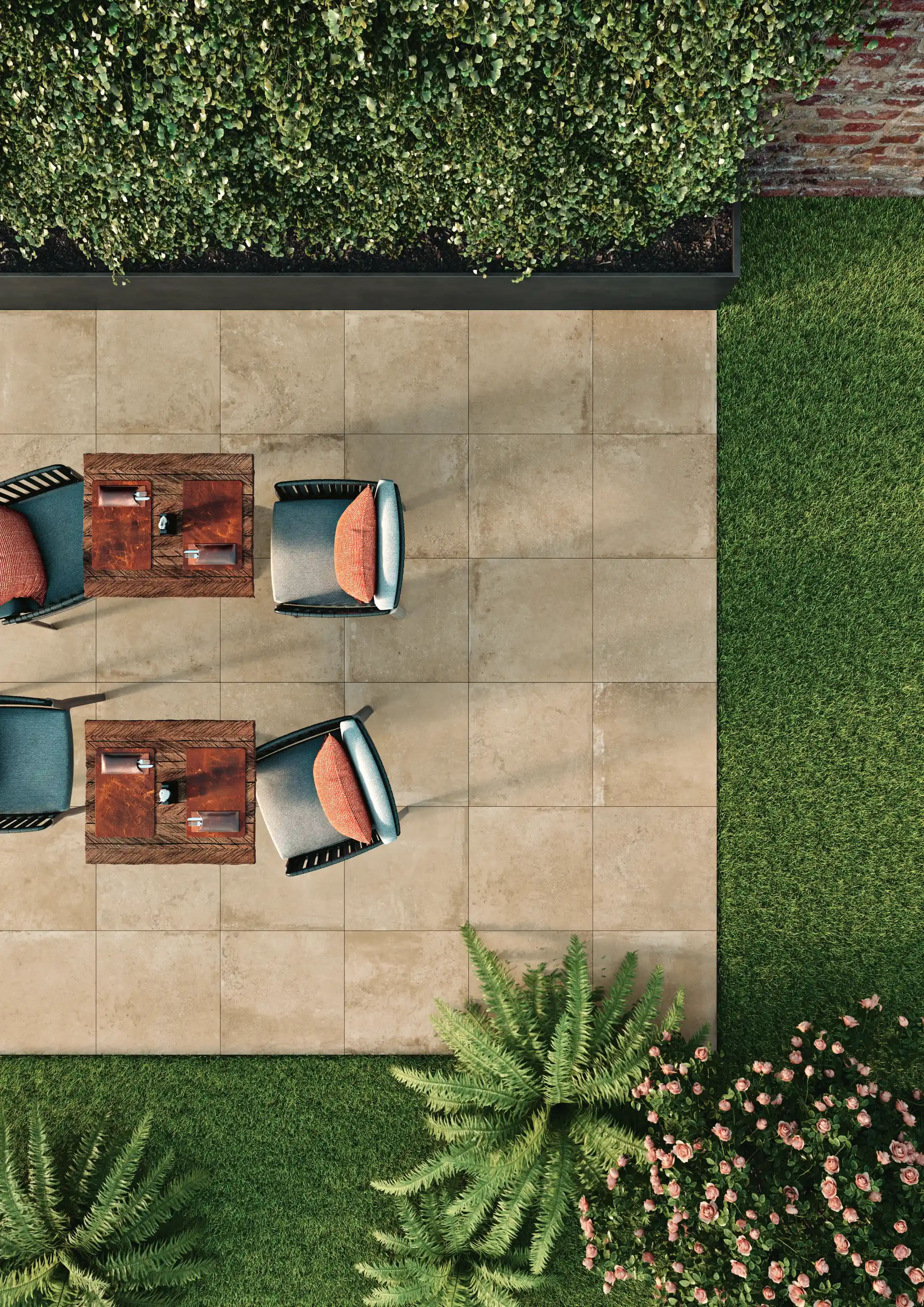 Top-down view of outdoor patio with two sets of chairs, tables, green bushes, and grass lawn.