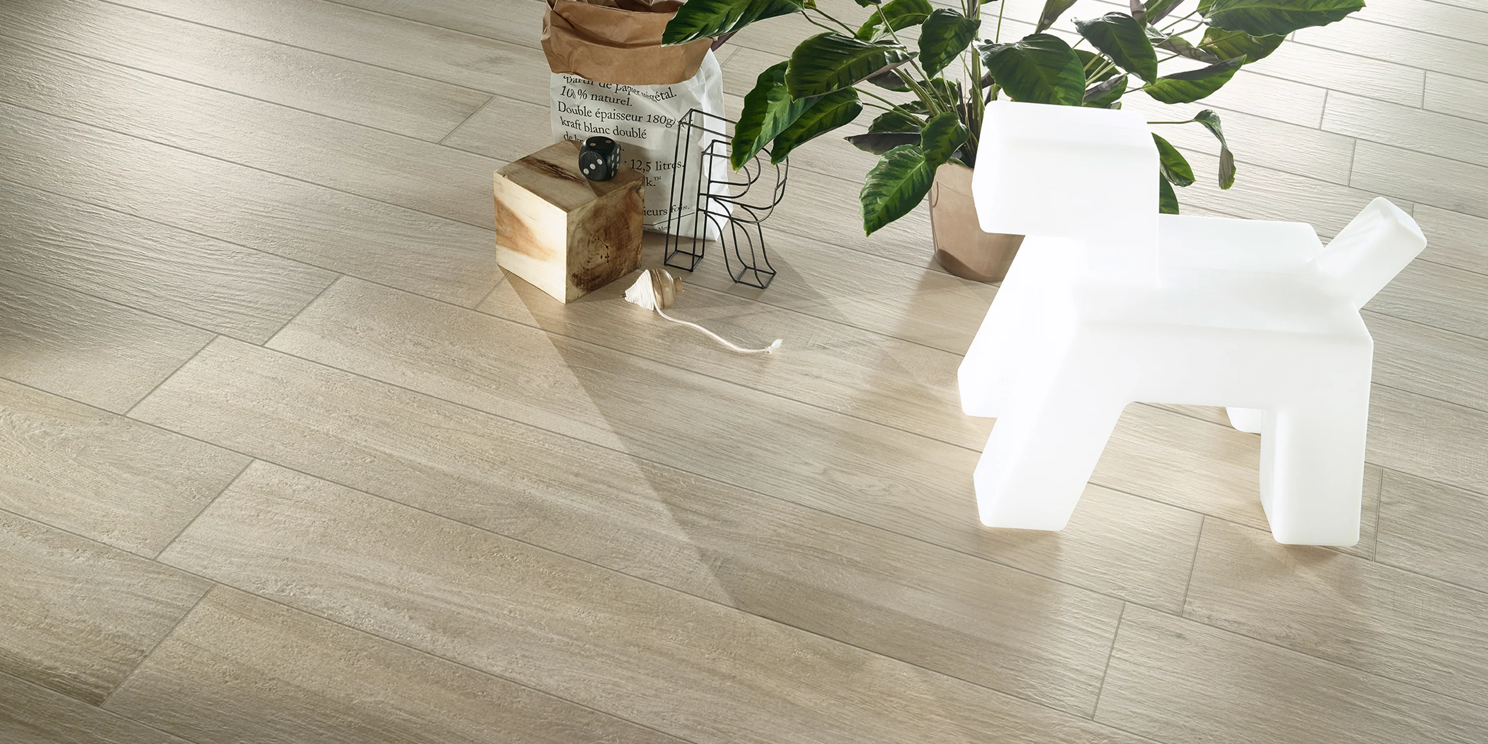 Light wood-style floor tiles with a white dog-shaped chair, potted plant, and decorative items.