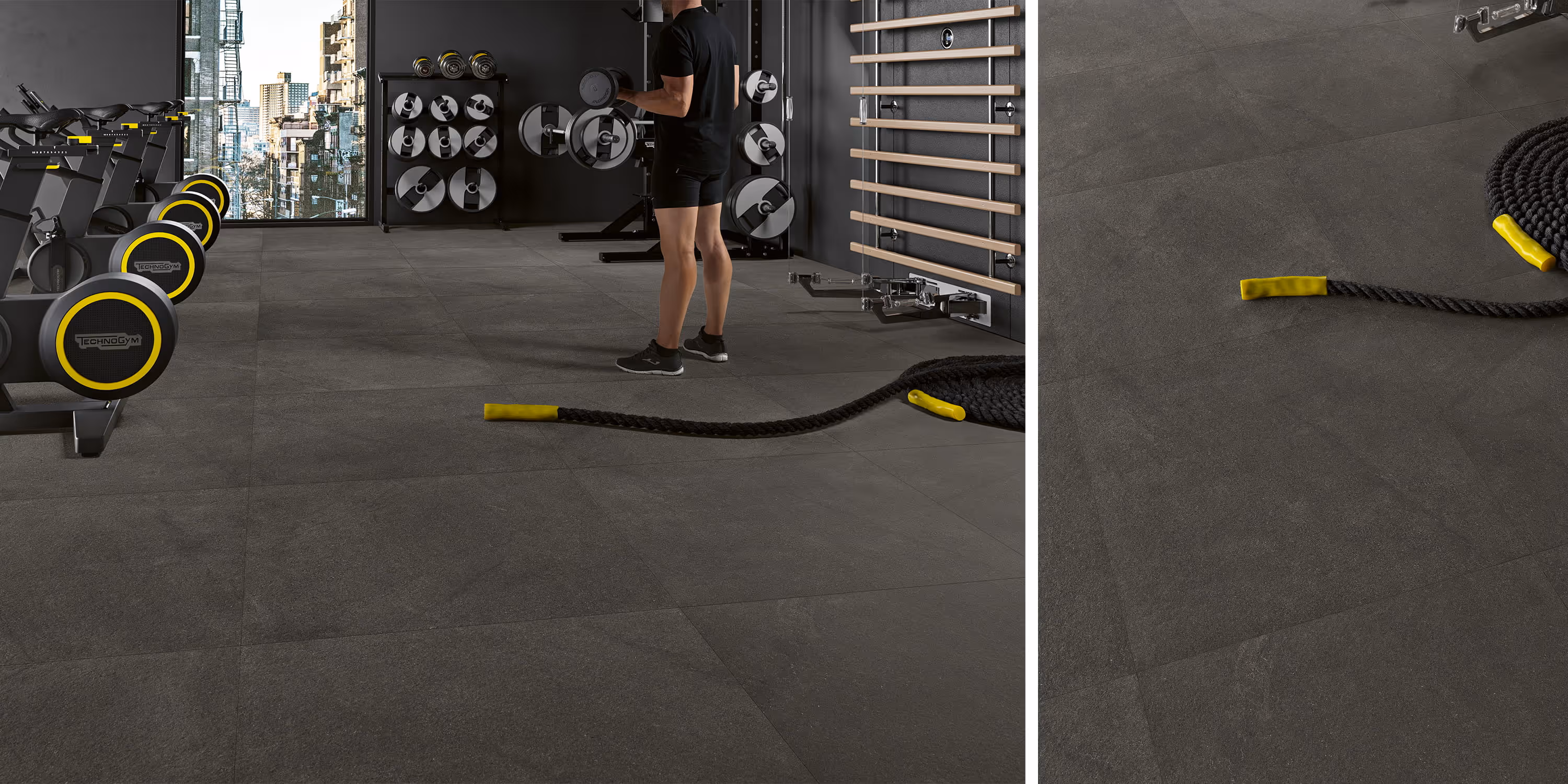 Modern gym with dark stone tile floor, exercise bikes, weight racks, and a man lifting dumbbells.