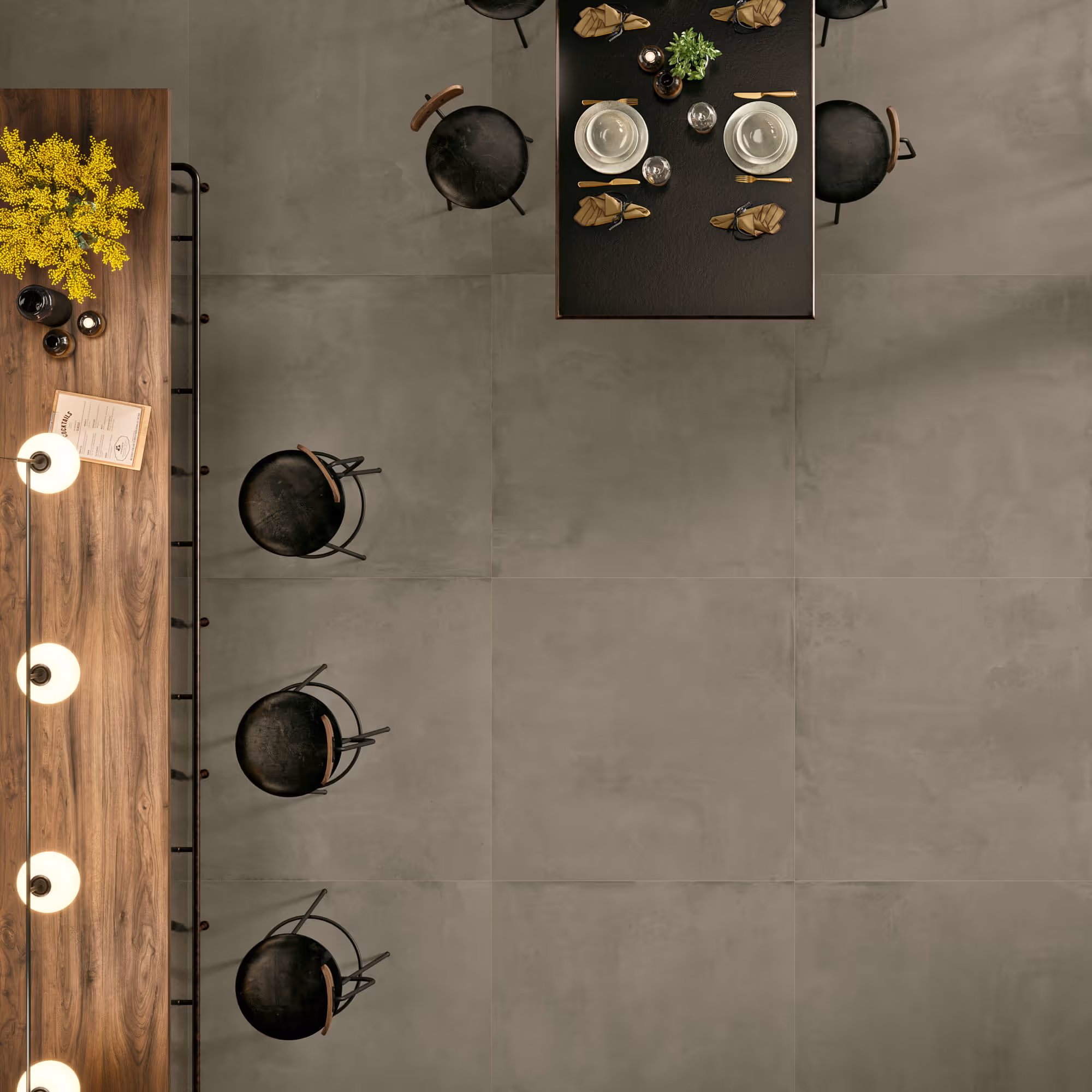 Top view of dining area with black chairs, black table set for two, and wooden counter with yellow flowers.