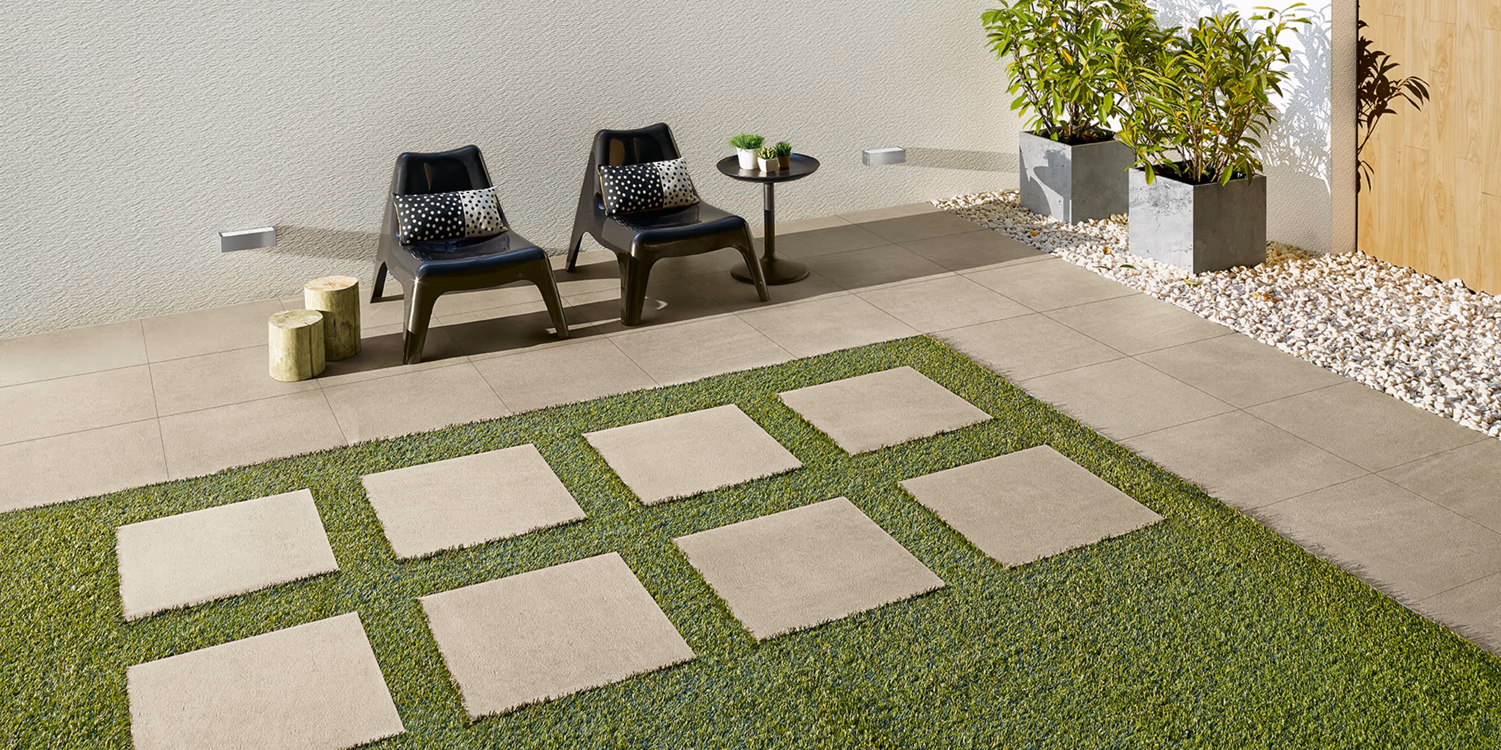 Outdoor space with modern black chairs, small table, potted plants, and large square stone tiles on grass.