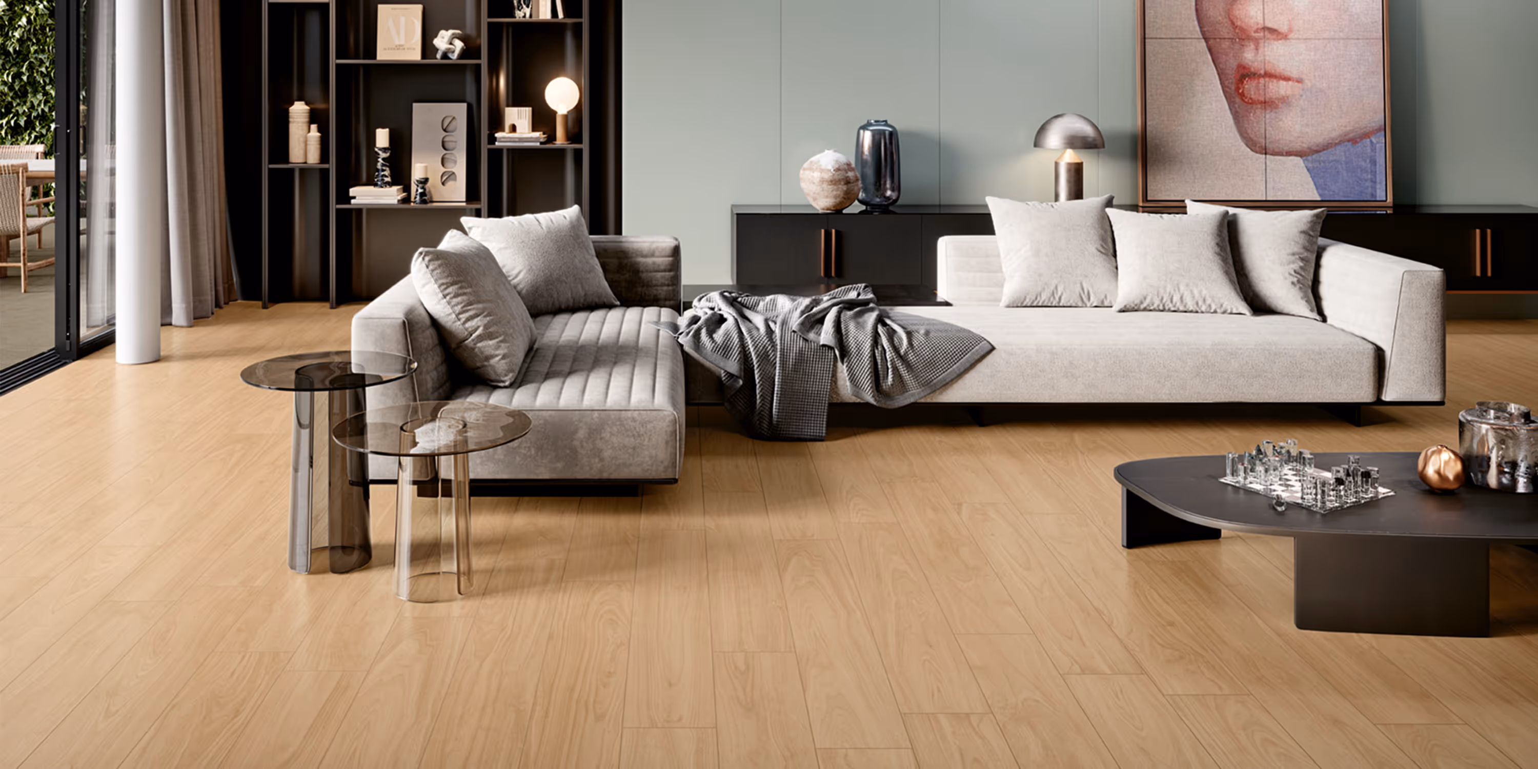 Modern living room with light wood floor, beige sectional sofa, glass side tables, and a chess set on a black coffee table.