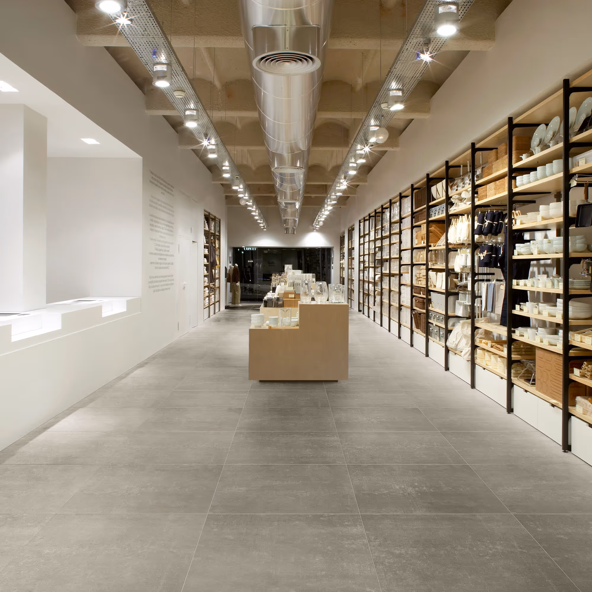 Modern store interior with wooden shelves holding kitchenware and home goods under ceiling lights.