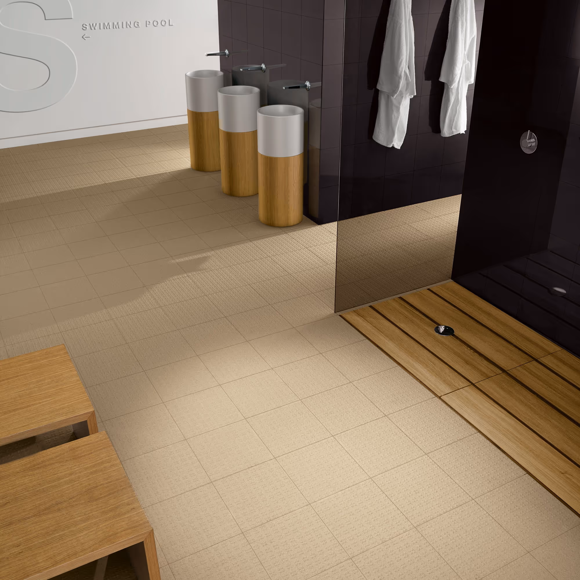 Modern bathroom with three pedestal sinks and wooden benches near a glass shower with robes hanging.