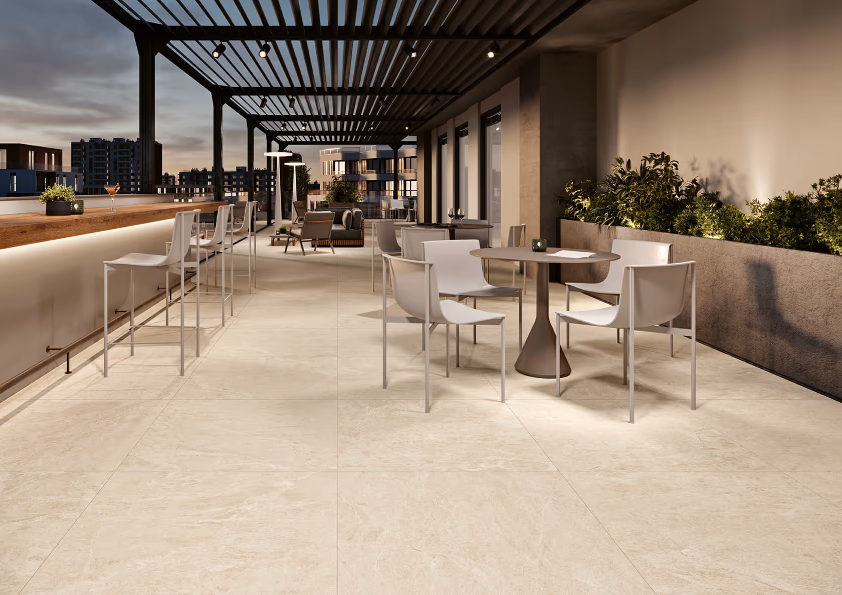 Modern rooftop patio with white chairs, round tables, bar stools, and plants at dusk.