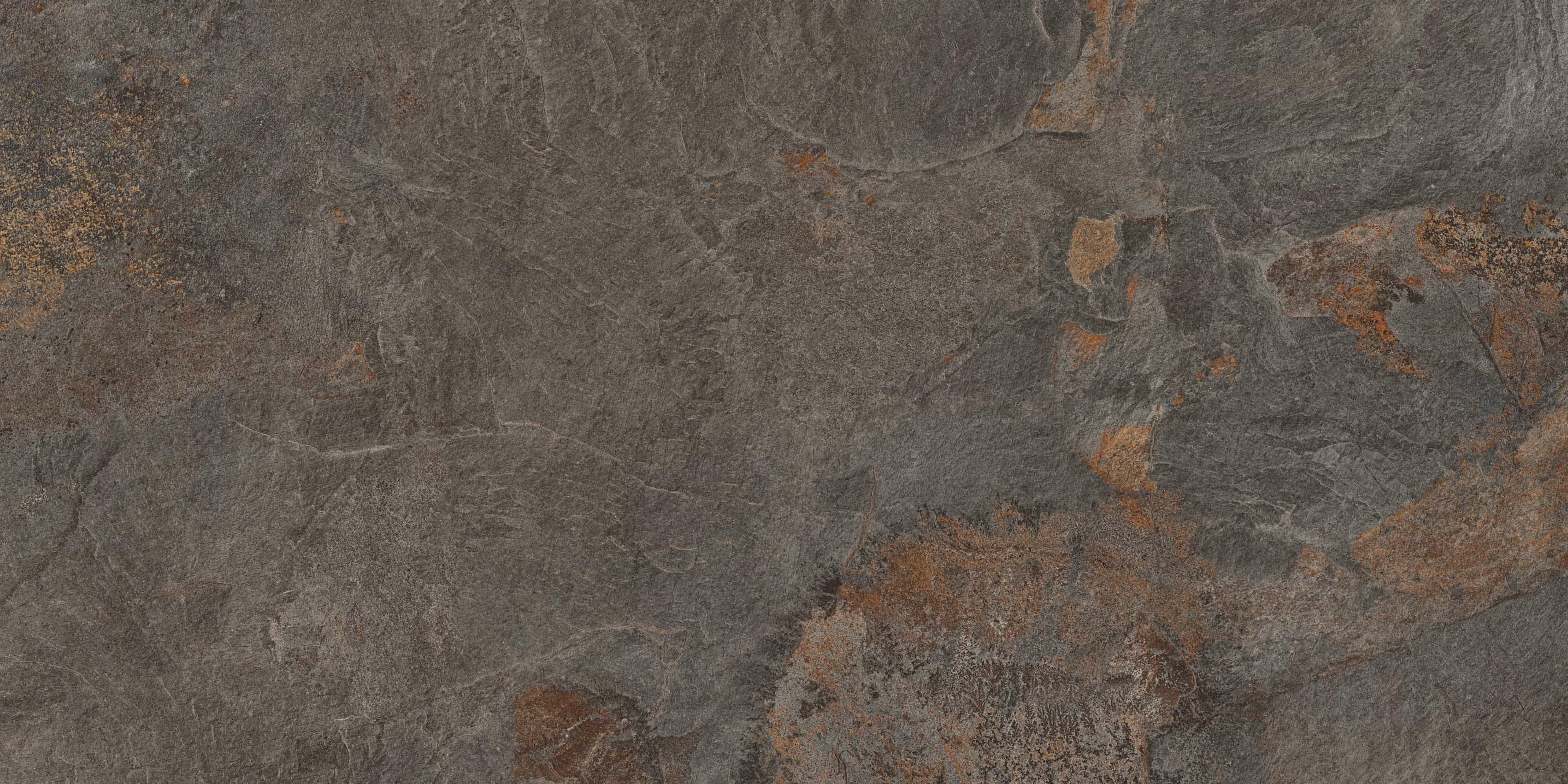 Close-up of rough textured stone surface with dark gray and rusty brown patches.